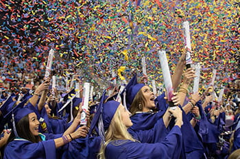 TCU graduates in caps and gowns set off handheld confetti cannons