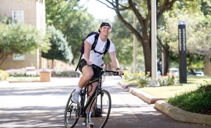 Male student riding a bike on campus